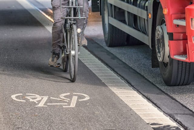 cyclist being overtaken by a truck in a bike lane